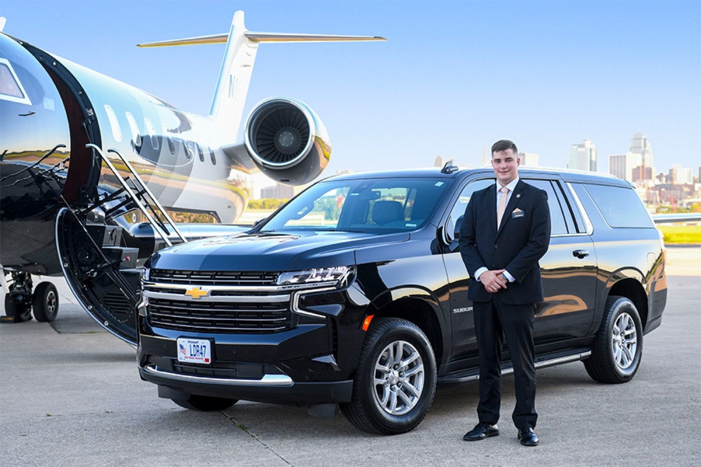 Chauffeur waiting beside a black SUV and private jet